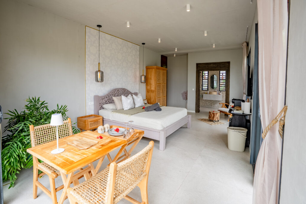 Oceanfront Hideaway Suite at Moorea Ocean Love, with a king-size bed, wooden dining table and private bathroom beyond.