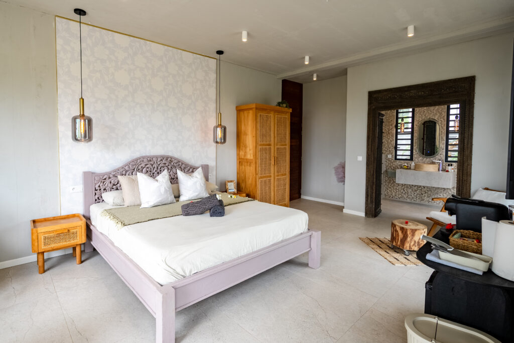 Elegant king-size bed with carved wooden headboard and natural furnishings in the Oceanfront Hideaway Suite.