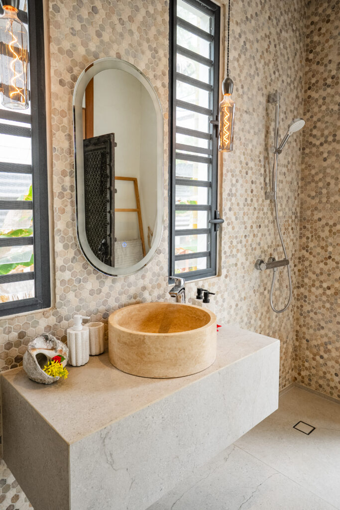 Private bathroom in the Oceanfront Hideaway Suite, with natural stone basin, walk-in shower and decorative mosaic tiles.