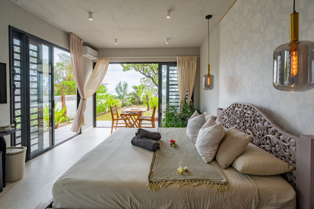 Romantic king-size bedroom opening onto a private wooden deck and seaside garden at Moorea Ocean Love.