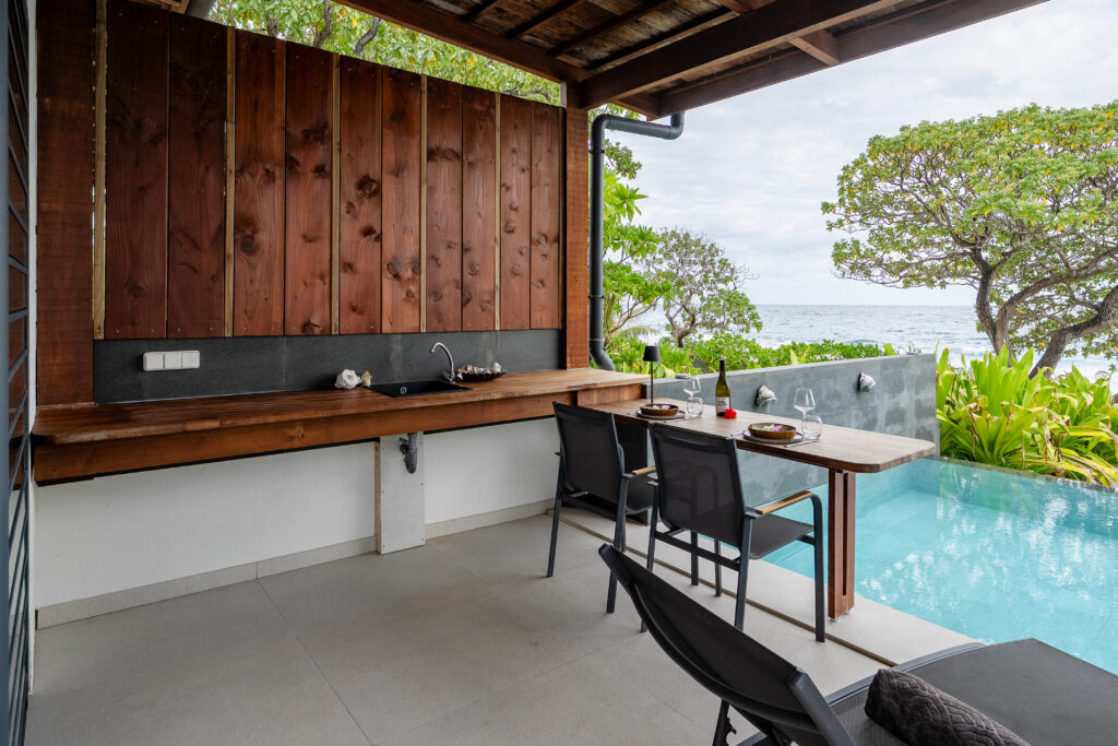 Private covered terrace with outdoor kitchenette, romantic dining table and infinity pool overlooking the Pacific Ocean.