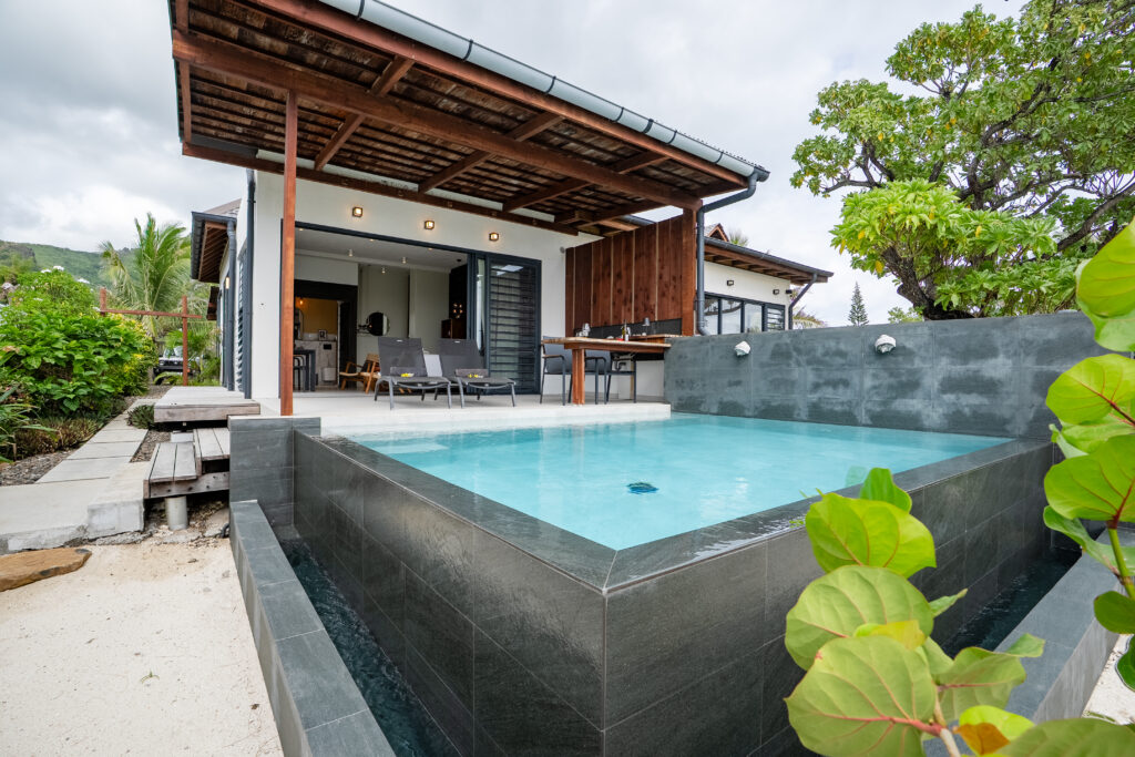 Private infinity pool with dark stone edges beside the Mirror Pool Suite's covered terrace.